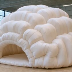 White inflatable walk-in dome installed on a timber floor inside a gallery space