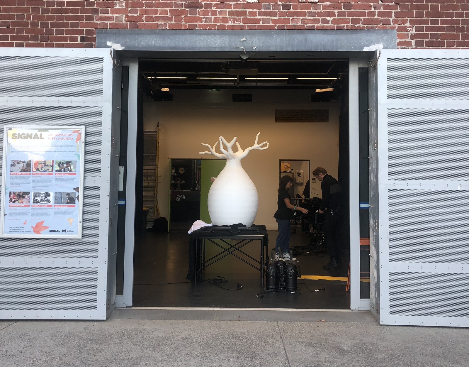 oddtoe baobab sculpture loading in signal doors melbourne Oddtoe's white 2.1-metre carved baobab sculpture seen through the open loading doors at Signal, the City of Melbourne's arts space on the Yarra, with crew setting up